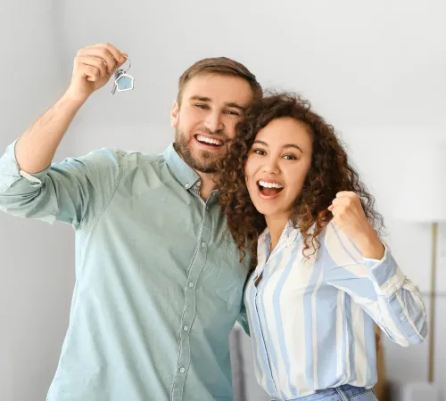 Couple cheering with house keys in hand.