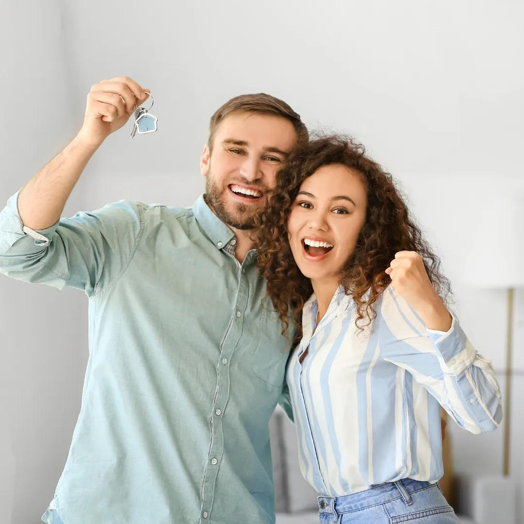 Couple cheering with house keys in hand.