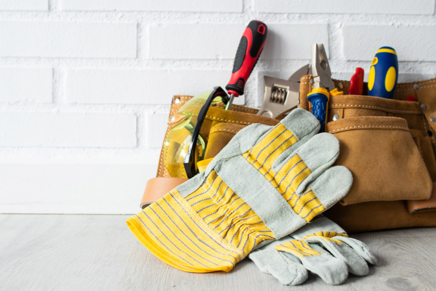 Memphis maintenance oversight property management with work gloves, tools, and measuring tape on a tile floor for rental repairs