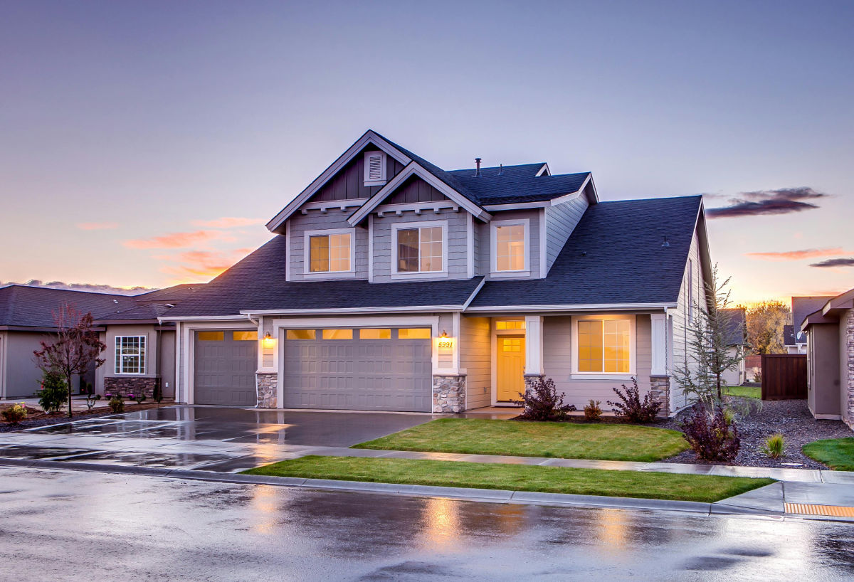 Modern suburban home at dusk with warm interior lights, driveway, and landscaped front yard, Management Boosts Rental Returns