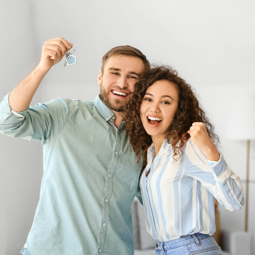 Couple cheering with house keys in hand.